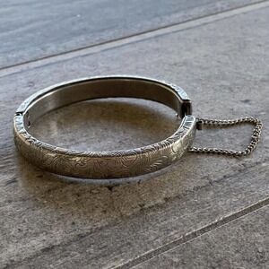 A beautiful vintage cuff bracelet with floral design features safety chain